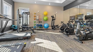 Une salle de sport équipée de tapis de course, de vélos elliptiques et de poids libres.