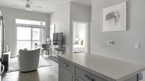Een moderne hotelkamer met een groot raam, een bureau met stoel, een bed en een plafondventilator.