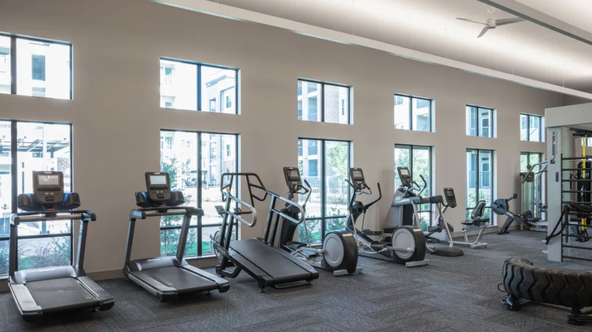 A gym with treadmills, elliptical machines, and a weight bench.