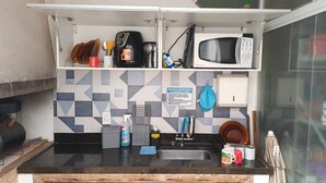 A compact kitchen with a microwave, coffee maker, and a sink.