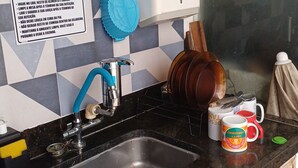 A kitchen with a sink, a blue towel, and a sign with maintenance rules.
