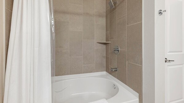 Un baño moderno con bañera, ducha y una puerta.