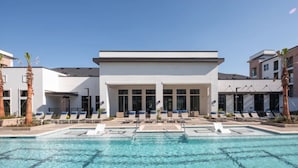 A modern hotel with a pool area, sun loungers, and a clear blue sky. - Landing | Modern 2BD, Gym, Pool (Round Rock)