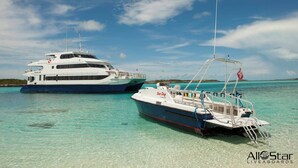 Two boats docked at a marina with clear turquoise water and a clear sky.