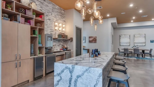 A modern kitchen with marble countertops, a built-in oven, and a dining area with a marble island and bar stools. - Landing | Amazing 2BD, Courtyard, Clubhouse (Haltom City)