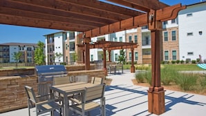 An outdoor patio with a grill, seating, and a pergola structure. - Landing | Amazing 2BD, Courtyard, Clubhouse (Haltom City)