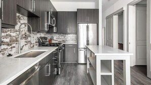 A modern kitchen with dark wood cabinets, stainless steel appliances, and a white countertop.