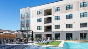 Un hôtel à plusieurs étages doté d’une piscine, d’un espace extérieur aménagé et d’un patio couvert.
