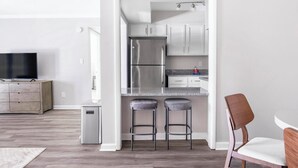 A modern kitchen with stainless steel appliances, a grey countertop, and two bar stools. - Landing | Amazing 1BD, Gym, Pool (Vestavia Hills)