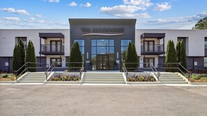 A modern building with a sign reading "The Brockwood." It features a central entrance with a glass facade, flanked by two symmetrical wings with balconies. - Landing | Amazing 1BD, Gym, Pool (Vestavia Hills)