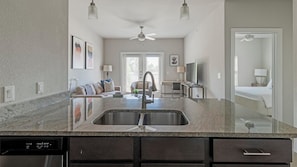 A modern kitchen with a large sink, dark cabinets, and a dining area with a table and chairs.