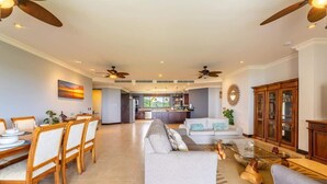 A spacious living room with a dining area, a kitchen in the background, and a large wooden cabinet. - Malinche 422B- Ocean view condo at Reserva Conchal (Reserva Conchal)