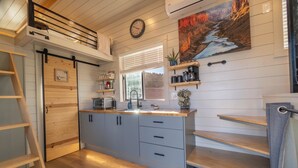 Une cuisine moderne avec des meubles en bois, une cuisinière encastrée et une fenêtre équipée de stores.