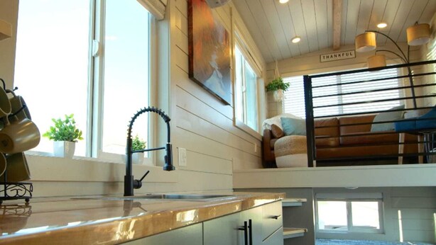 Une cuisine moderne avec un plan de travail en bois, un robinet noir et un porte-ustensiles.