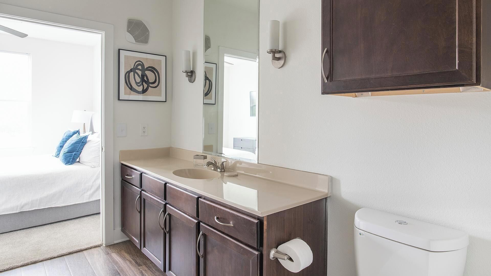 Une salle de bain avec un double lavabo, des meubles en bois foncé, des toilettes et un grand miroir.