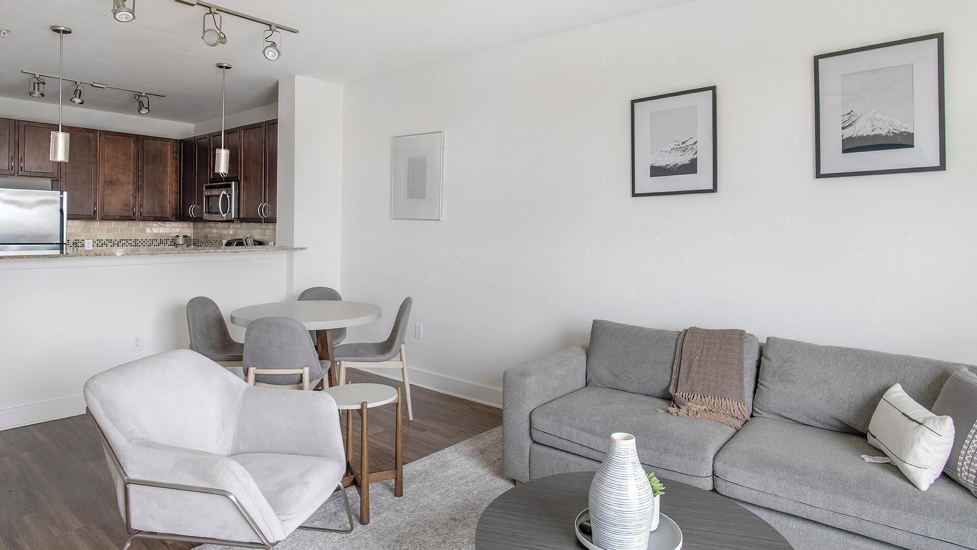 Un salon moderne avec un canapé gris, une table basse et un coin repas comprenant des chaises et une table.