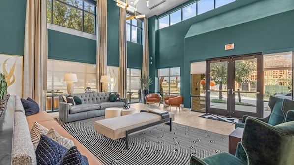 A spacious lobby with a grey sofa, a coffee table, and a patterned rug.