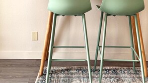 A modern room with a desk, two green chairs, a framed picture, and a small plant. - Ocean Cove Inn #4 – Ocean View (Yachats)