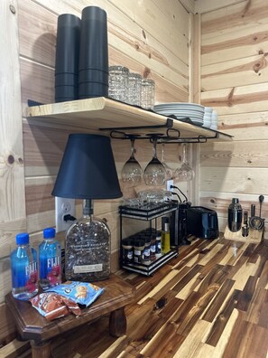 Un coin cuisine avec des murs en bois, une lampe noire, une machine à café, un grille-pain et divers ustensiles de cuisine.