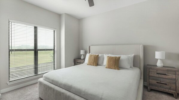 A bedroom with a large bed, two bedside tables with lamps, and a window with blinds. - Landing | Stunning 1BD, Clubhouse, Courtyard (Katy)