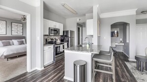 Une cuisine moderne avec des meubles blancs, un plan de travail en granit et une hotte en acier inoxydable.