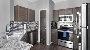 A modern kitchen with stainless steel appliances, a dishwasher, and a microwave. - Landing | Stunning 1BD, Gym, Pool (Haltom City)