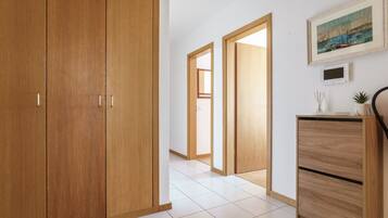 A hallway with wooden wardrobes, a tiled floor, and a painting on the wall.