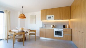 A modern kitchen with wooden cabinets, a microwave, an oven, and a dining area with a round table and chairs.