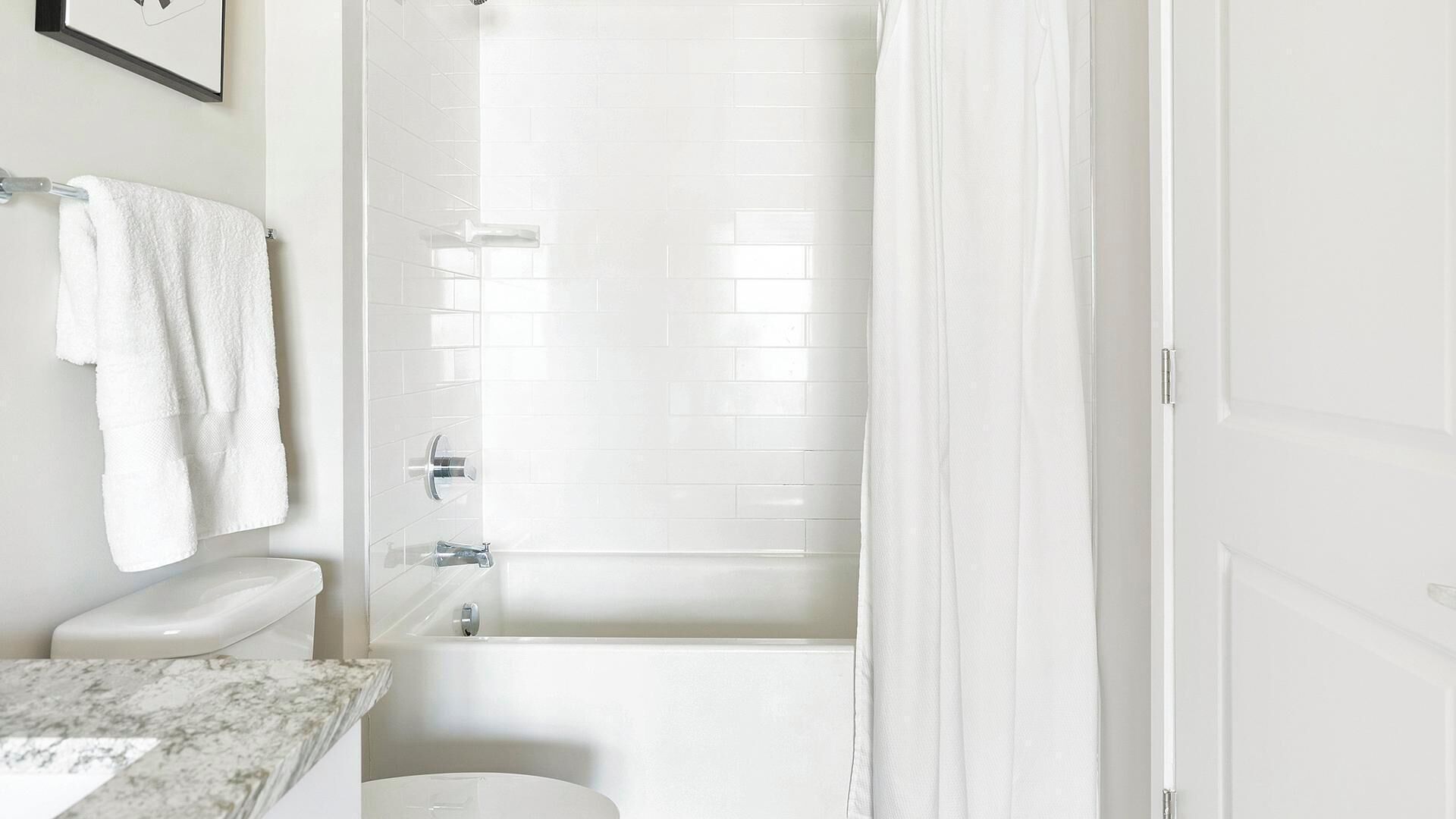 Un baño con inodoro blanco, lavabo con encimera de mármol y bañera.