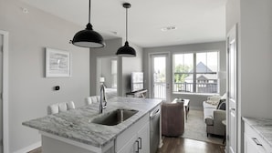 A modern kitchen with a marble countertop, a built-in sink, and pendant lighting.
