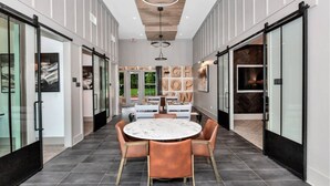 A modern interior with a round marble table, leather chairs, and a view of a garden through glass doors. - Landing | Modern 2BD, Clubhouse, Pool (Huntsville)