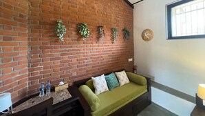 Una habitación con pared de ladrillo, sofá verde y ventana con barrotes.