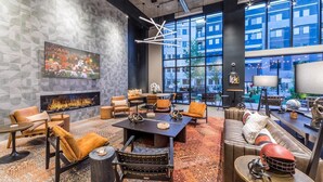 Een moderne lounge met een open haard, comfortabele zithoek en grote ramen met uitzicht op de stad.