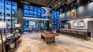 Een moderne bar met een pooltafel, barstoelen en een televisiescherm.