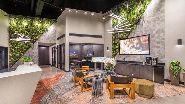 Een moderne lobby met een receptiebalie, zithoek en een groot televisiescherm.