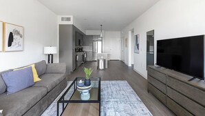 A modern living room with a sofa, coffee table, and TV. - Landing | Spectacular 1BD, Gym, Courtyard (Spring Valley)