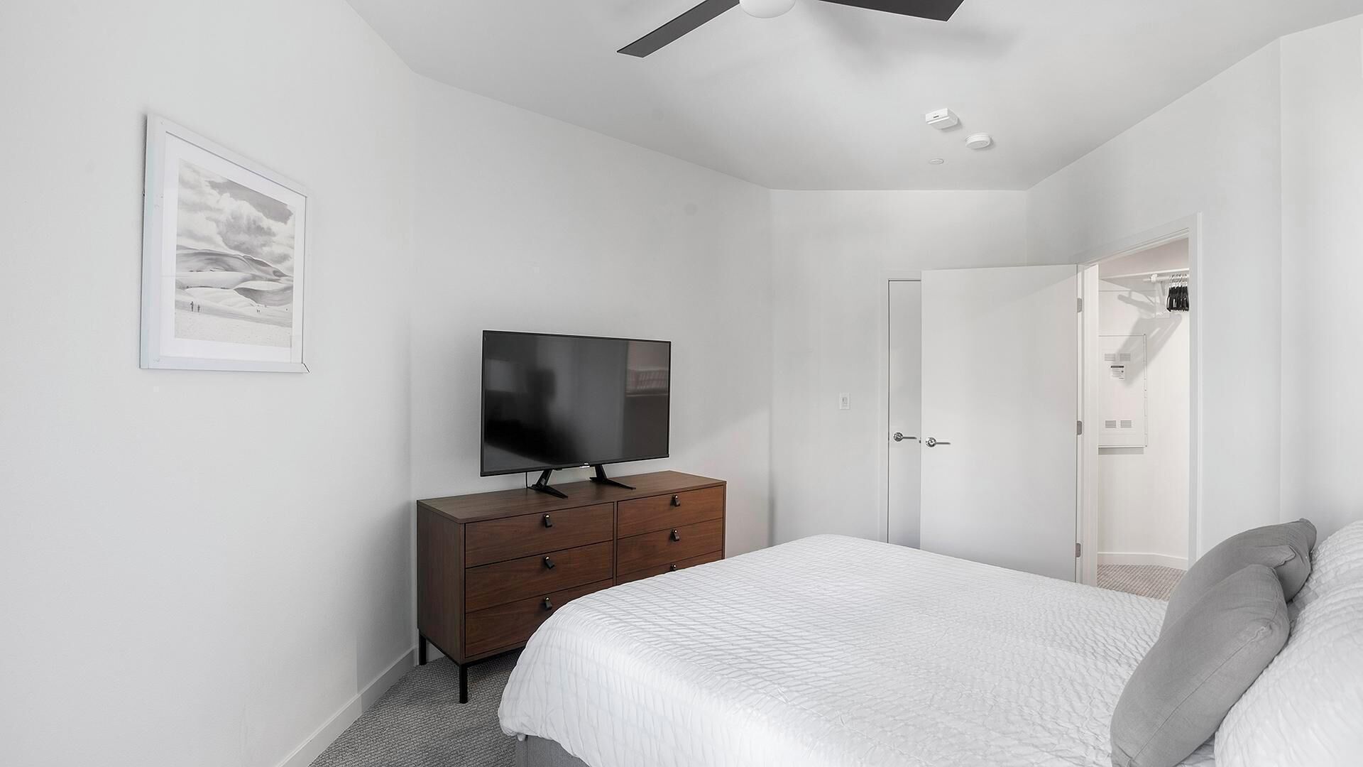Une chambre à coucher avec un lit, un téléviseur posé sur une commode, une porte et un placard.