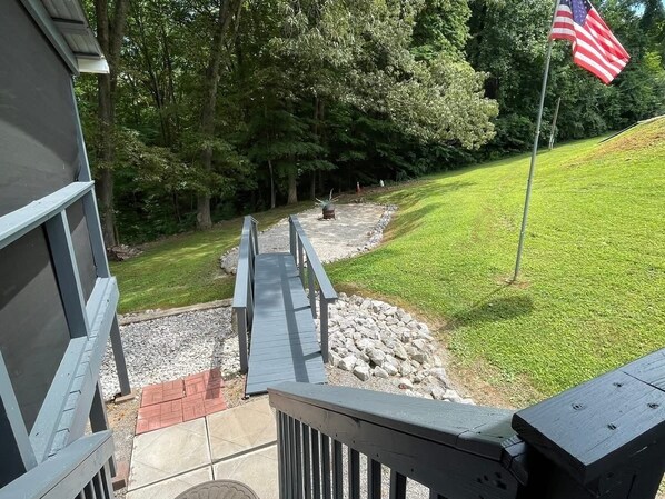 A wooden deck leading to a stone pathway with a flagpole and flag.