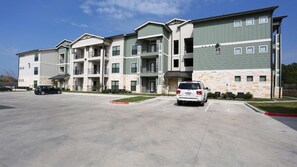 A multi-story apartment building with a parking lot in front.