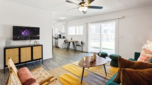 A modern living room with a sofa, a coffee table, and a dining area with a table and chairs. - Sunrise Vista-walk to Downtown Old Town & Bars! (Scottsdale)