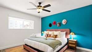A bedroom with a bed, a ceiling fan, a window, and a nightstand with a lamp. - Sunrise Vista-walk to Downtown Old Town & Bars! (Scottsdale)
