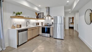 A modern kitchen with white cabinetry, stainless steel appliances, and a central island. - Euphony-designer Furnishings-5 Mins to Broadway (Nashville)