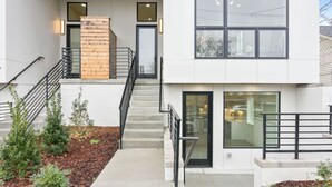 A modern two-story building with a staircase, a stone accent wall, and a glass door. - Euphony-designer Furnishings-5 Mins to Broadway (Nashville)