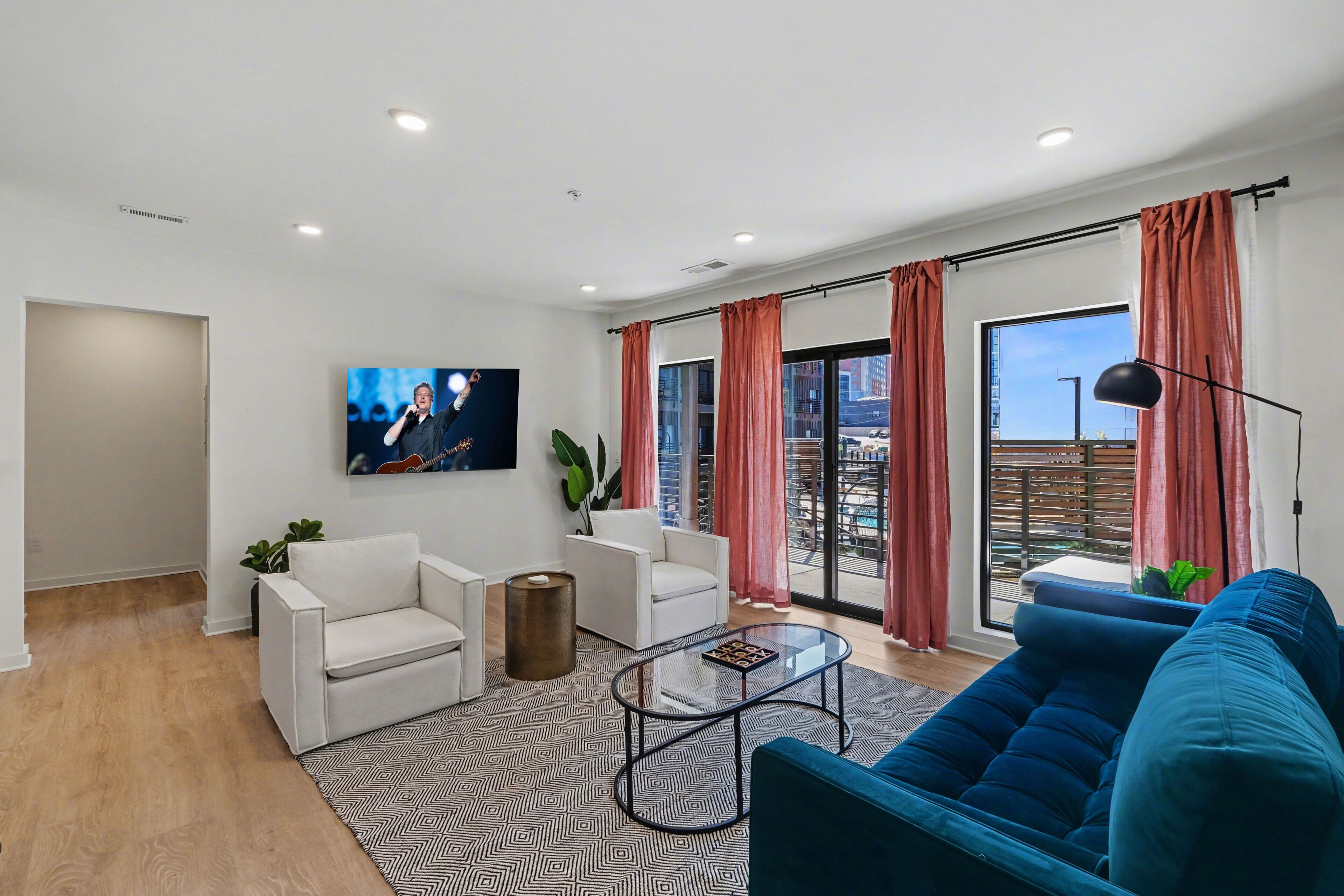 Una sala de estar moderna con un sofá, sillones, una mesa de centro y un televisor montado en la pared.