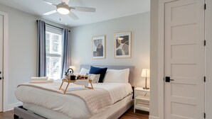 Un dormitorio con cama, mesita de noche, lámpara y ventilador de techo.