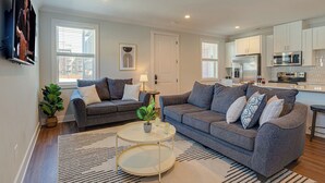 A modern living room with two grey sofas, a coffee table, and a potted plant. - Modern Melrose-sleeps 8- Mins to Downtown Broadway (Nashville)