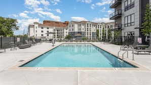 A swimming pool with lounge chairs and a fence, surrounded by multi-story buildings. - Vandy Vinyl - Odyssey -pool & Gym-mins to Broadway (Nashville)