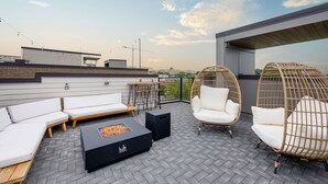 A rooftop terrace with a modern outdoor seating area, including a sofa set and wicker chairs, and a fire pit table. - Vivid Vocals - 4 Mins to Broadway - Rooftop Patio (Nashville)