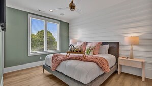 Un dormitorio con cama, mesita de noche, lámpara y ventana.