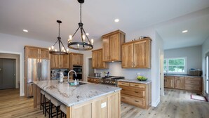 A modern kitchen with wooden cabinets, a large island, stainless steel appliances, and a chandelier. - Majestic Manor-private Hundred Acre Yard-pool/spa (Lebanon)